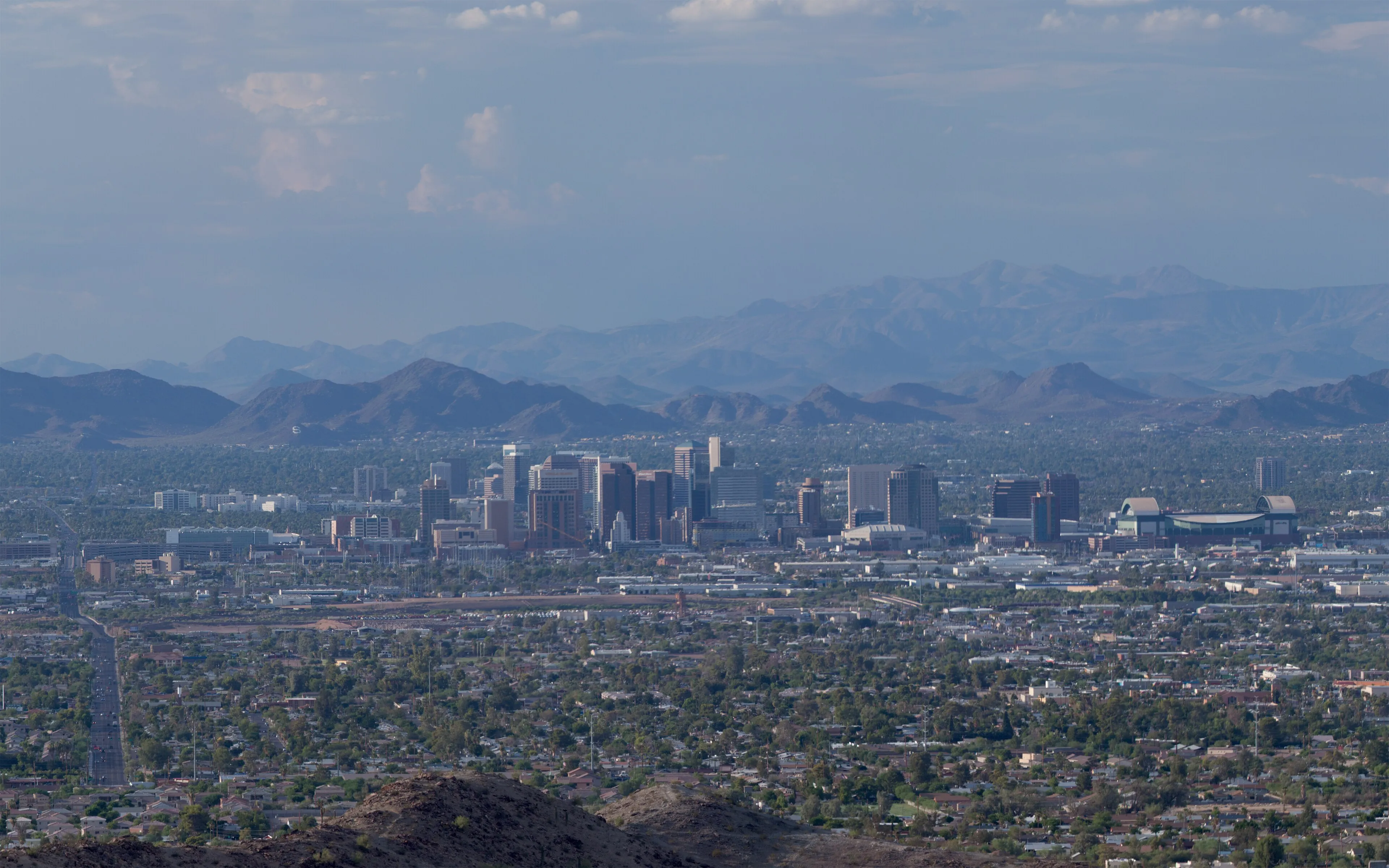 The Phoenix skyline during daytime with scattered clouds and a bright blue sky